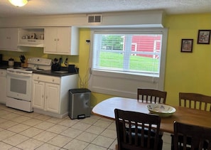A kitchen with white cabinets, a stove, and a dining table with chairs. - Mountain View Farmhouse (Stanardsville)