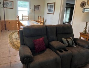 A living room with a sofa, a dining table with chairs, and a floor lamp. - Mountain View Farmhouse (Stanardsville)