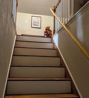 A staircase with wooden steps and a handrail, leading to a landing with a framed picture. - Mountain View Farmhouse (Stanardsville)