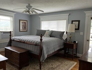 A bedroom with a four-poster bed, a wooden dresser, a nightstand, a lamp, and a ceiling fan. - Mountain View Farmhouse (Stanardsville)