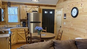 Une cuisine rustique avec des meubles en bois, un réfrigérateur en acier inoxydable et une table à manger avec des chaises.