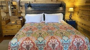 Une pièce aux murs lambrés, comprenant un lit, une table de chevet, une commode et une lampe.