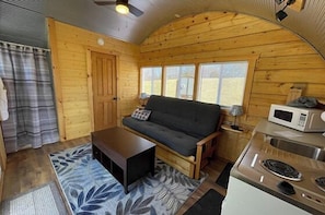 A compact cabin with a sofa, coffee table, and kitchenette. - Bamboo Beetle Cabin Pod (Stanardsville)