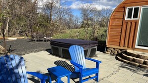 An outdoor patio with two Adirondack chairs, a small table, and a barbecue grill. - Bamboo Beetle Cabin Pod (Stanardsville)