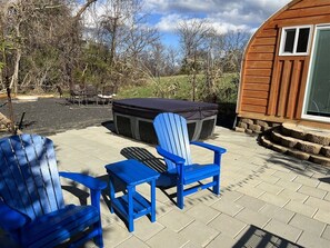 An outdoor patio with two Adirondack chairs, a small table, and a barbecue grill. - Bamboo Beetle Cabin Pod (Stanardsville)