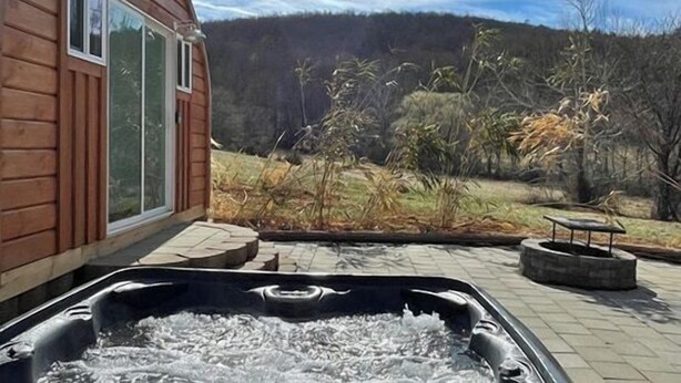 A wooden cabin with a hot tub and a patio area. - Bamboo Beetle Cabin Pod (Stanardsville)