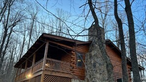 A log cabin with a balcony, stone foundation, and surrounded by trees. - Sweet Reunion Mountain Cabin (Stanardsville)