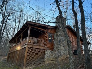 A log cabin with a balcony, stone foundation, and surrounded by trees. - Sweet Reunion Mountain Cabin (Stanardsville)