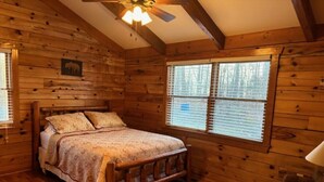 A wooden cabin bedroom with a bed, a ceiling fan, and a window with blinds. - Sweet Reunion Mountain Cabin (Stanardsville)