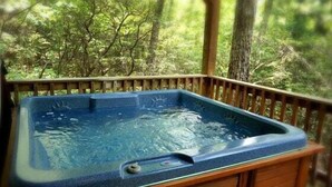 A hot tub on a wooden deck with a forest backdrop. - Cabin #5 - Love Nest (Stanardsville)
