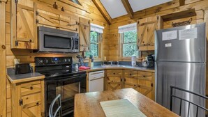 A wooden cabin-style kitchen with a stainless steel refrigerator, microwave, stove, and dishwasher. - Cabin #5 - Love Nest (Stanardsville)