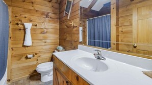A wooden cabin-style bathroom with a white sink, mirror, and wooden walls. - Cabin #5 - Love Nest (Stanardsville)