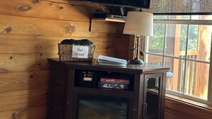 A wooden interior with a TV mounted on the wall, a fireplace, and a window with a view. - My Lakeview Mountain Cabin (Stanardsville)