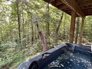 A hot tub in a forested area with a wooden deck overhead. - Cabin #3 - Honey Pot (Stanardsville)