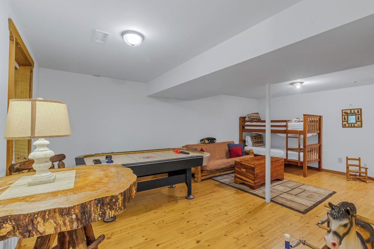 A room with a pool table, a sofa, a bunk bed, and a horse sculpture.