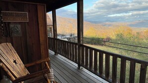 Eine Holzdiele mit Blick auf Herbstlaub und Berge.