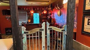 Eine Bar mit Theke, Holzwandverkleidung und einem Neonzeichen.