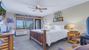 Un dormitorio con cama, escritorio, silla, ventilador de techo y ventana con persianas.