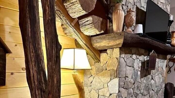 Un interior rústico con chimenea de piedra, vigas de madera y un sofá de cuero.