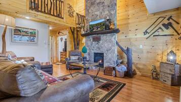 A cozy log cabin interior with a fireplace, leather sofa, and rustic decor.