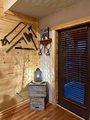 Un interior de madera con una puerta, un farol y herramientas en la pared.