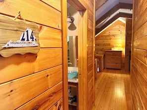 A wooden cabin interior with a wooden wall sign, a blue glass sink, and a wooden cabinet.