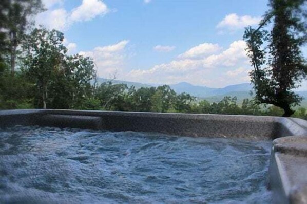 A hot tub with a view of trees and mountains.