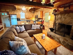 A cozy cabin interior with a living room, kitchen, and stone fireplace. - The Crooked Oak Cabin (Stanardsville)