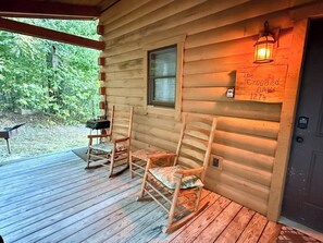 A wooden cabin with a porch, rocking chairs, a lantern, and a sign reading 'The Crooked Oak 1214'. - The Crooked Oak Cabin (Stanardsville)