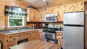 Une cuisine de style rustique, avec des meubles en bois, un réfrigérateur en acier inoxydable, un four à micro-ondes, une cuisinière et une table à manger.
