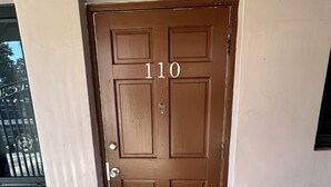 A brown door with the number 110, a doormat with "Welcome to our home" text, and a window to the left. - Cozy apartment in Hollywood. Ideal Location Near Beach, Shops, and Highways (Hollywood)