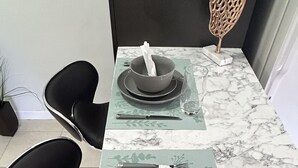 A dining table set with plates, bowls, cutlery, and napkins on a marble countertop. - Cozy apartment in Hollywood. Ideal Location Near Beach, Shops, and Highways (Hollywood)