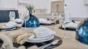 A dining table set with white plates, silverware, and blue glassware. - High Cotton: Private beach steps away, Heated pool, Brand new luxury home (Miramar Beach)
