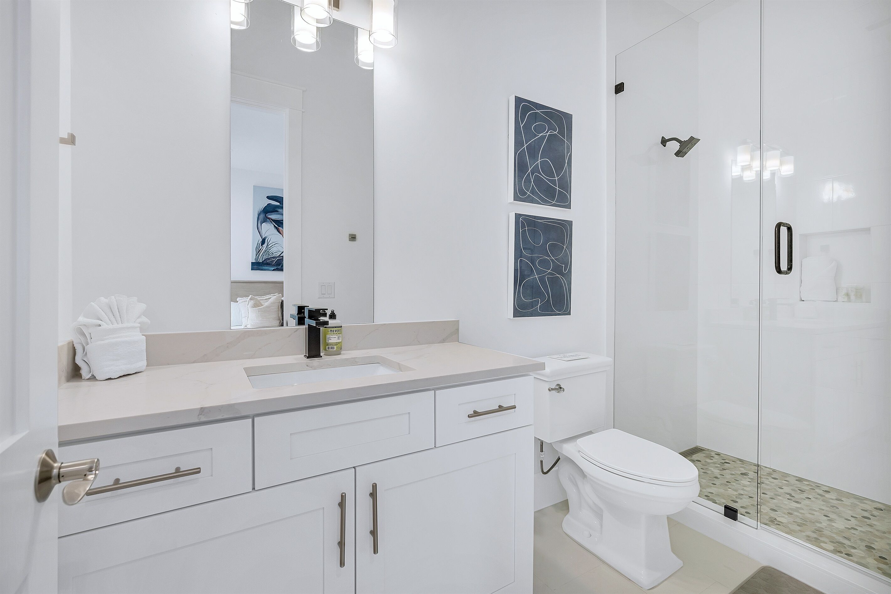 A modern bathroom with a white sink, toilet, and glass shower enclosure.