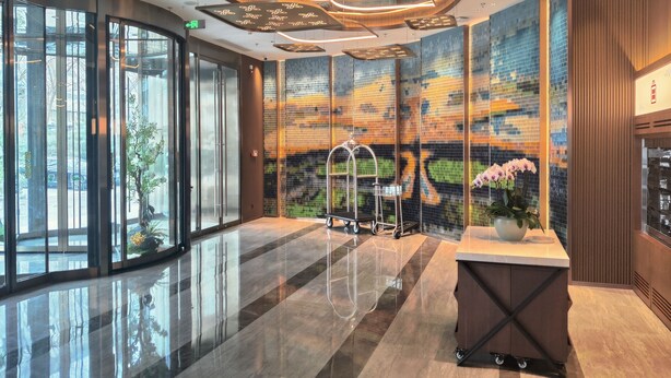 Un vestíbulo moderno con entrada de cristal, techo decorativo y pared con diseño.