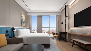 Una habitación de hotel moderna con una cama grande, un sofá, un escritorio y un televisor.