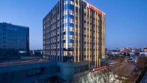 Un hotel moderno con fachada curva, ventanas amplias y señalización iluminada.