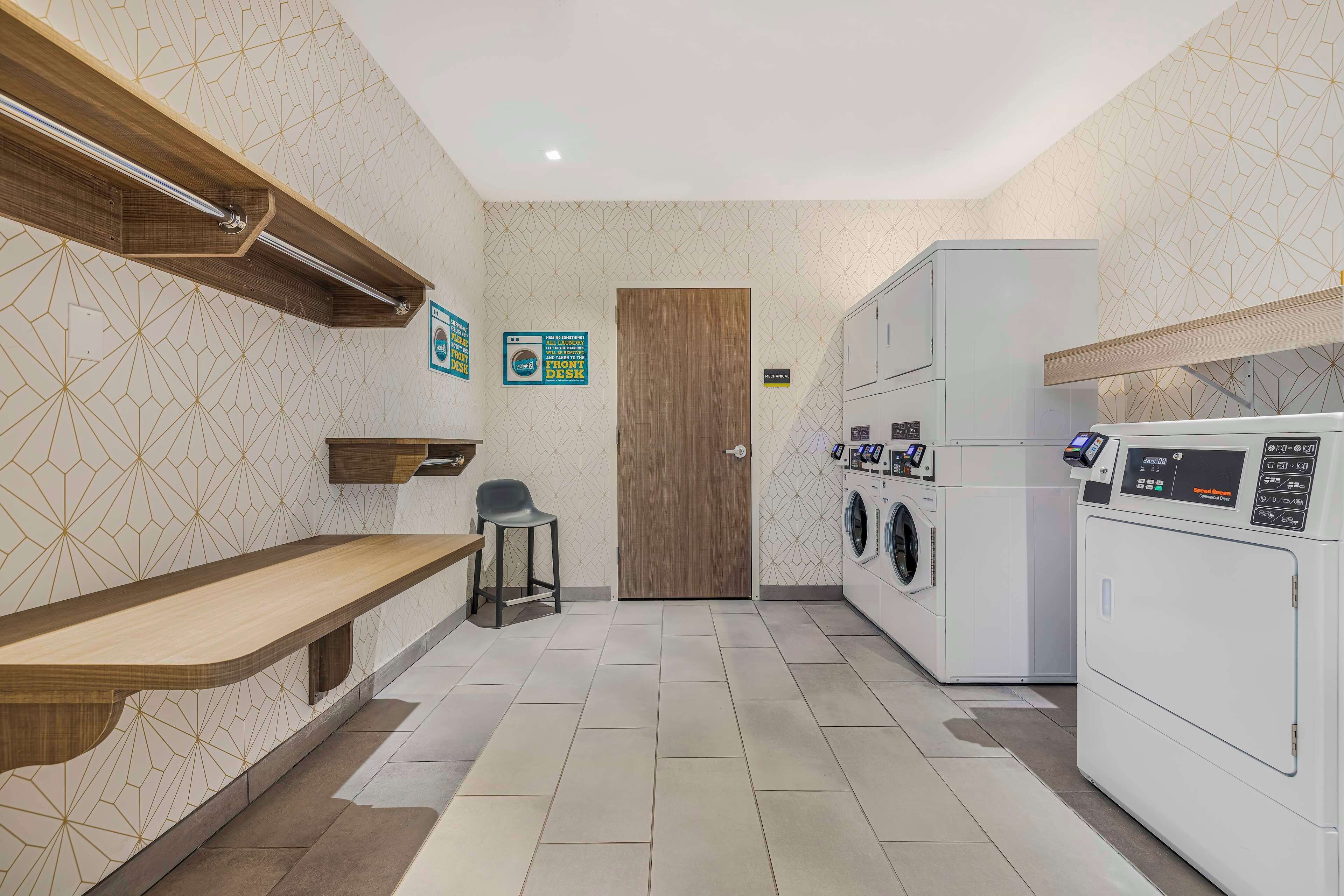 A laundry room with a wooden bench, washing machines, and a door.
