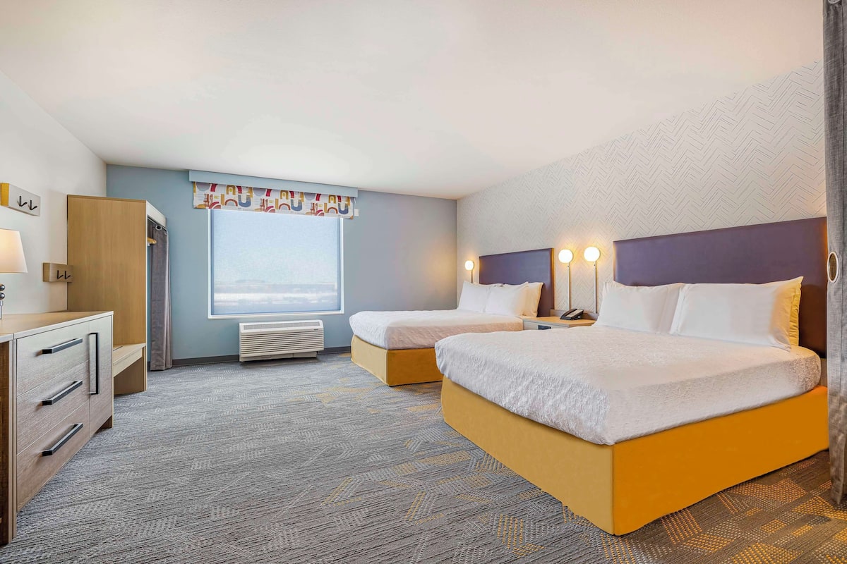 Une chambre d’hôtel avec deux lits, un bureau et une fenêtre donnant sur un paysage agréable.