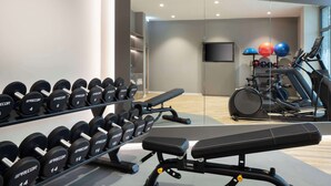 A gym with weightlifting equipment, a bench, and cardio machines. - Hampton By Hilton Celle (Celle)