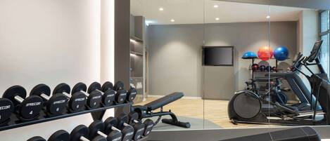 A gym with weightlifting equipment, a bench, and cardio machines.