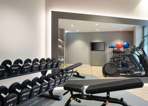 A gym with weightlifting equipment, a bench, and cardio machines. - Hampton By Hilton Celle (Celle)