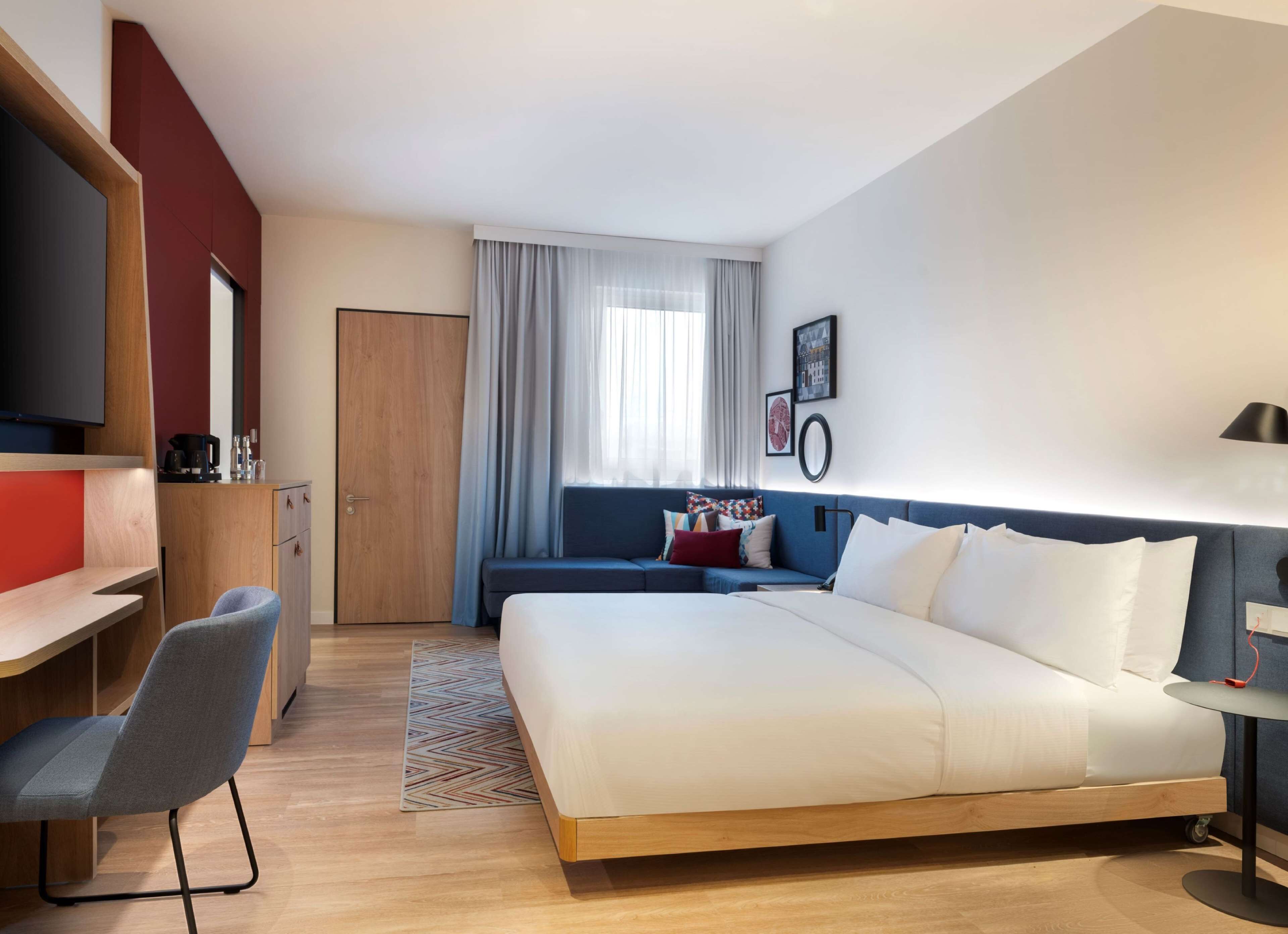 Une chambre d’hôtel moderne équipée d’un grand lit, d’un bureau, d’une chaise et d’un canapé.