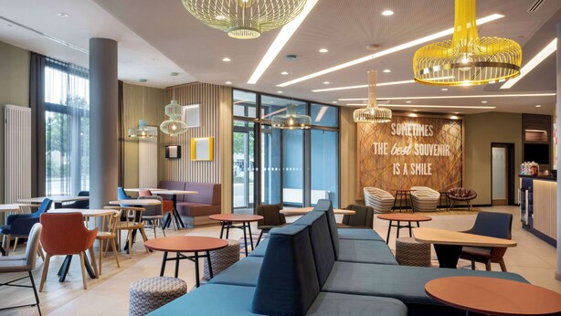 A modern lounge area with seating arrangements, pendant lighting, and a motivational quote on the wall. - Hampton By Hilton Celle (Celle)