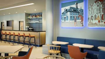 Un restaurant moderne doté d’un bar, de différents espaces pour s’asseoir et d’une projection d’un bâtiment sur le mur.