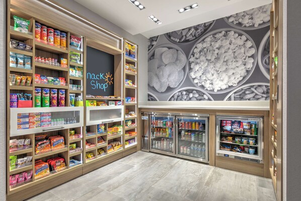 A snack shop with shelves stocked with various snacks and a neon sign that reads "Nacho Shop". - Hampton Inn & Suites Shenandoah The Woodlands, Tx (Shenandoah)