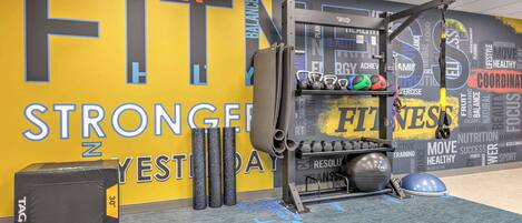 A gym with a motivational wall, exercise equipment, and a mat.