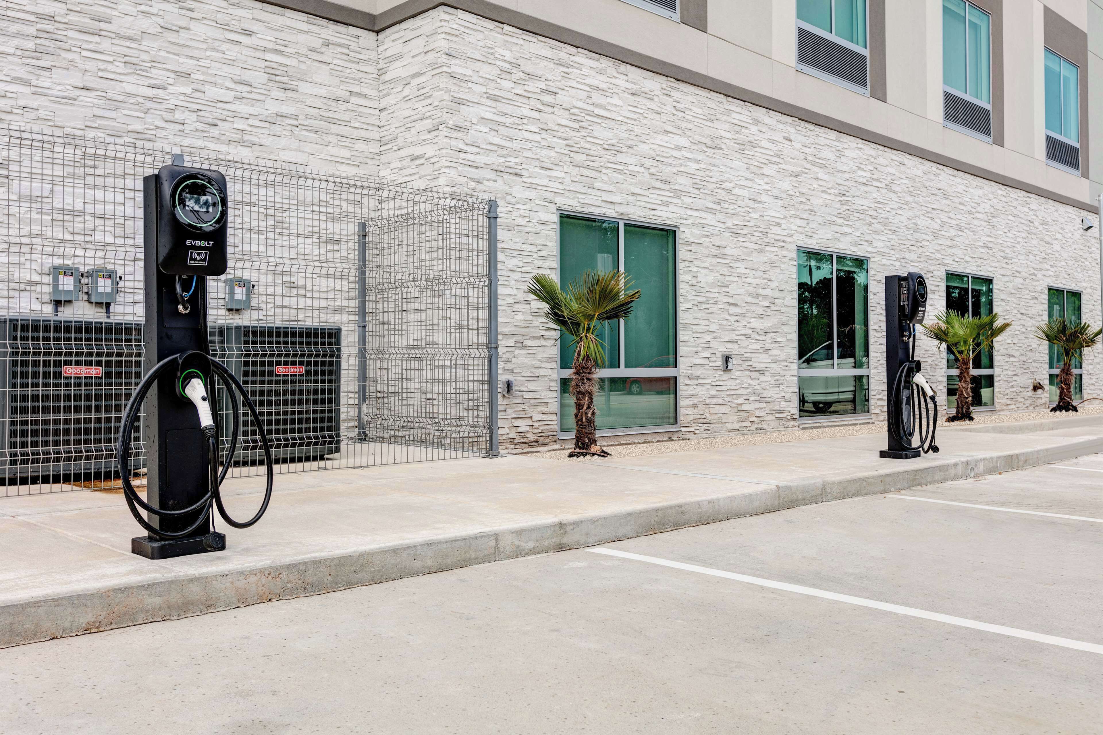 A modern building with a stone facade, multiple EV charging stations, and a gated entrance.