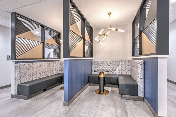 A modern waiting area with a central seating area, a patterned wall, and geometric ceiling design. - Hampton Inn & Suites Shenandoah The Woodlands, Tx (Shenandoah)