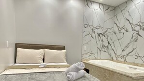Quarto moderno com cama, espelho grande e banheira.